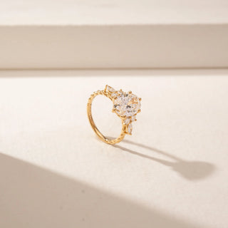 Angled view of a 14KT Yellow Gold diamond ring featuring an oval centre diamond, marquise and round diamond accents, and a prong setting.