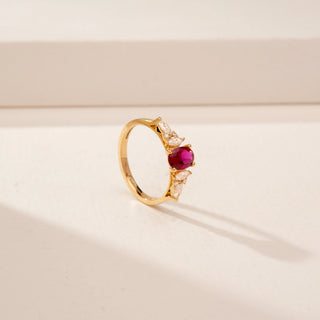 Angled view of a 14KT Yellow Gold diamond ring, featuring an oval red centre stone and pear-shaped diamonds.