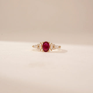 Front view of a 14KT Yellow Gold diamond ring, featuring an oval red centre stone and pear-shaped diamonds.