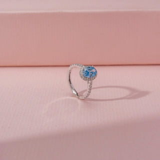 Angled view of Oval Blue Diamond Halo Ring in 14KT White Gold, featuring a blue oval diamond with a sparkling halo.