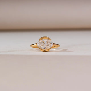 Front view of Modern Half Bezel Diamond Ring in yellow gold, featuring an oval lab-grown diamond secured in a sleek half-bezel setting, displayed on a soft beige backdrop.