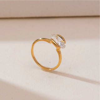 Angled side view of Modern Half Bezel Diamond Ring in yellow gold, showcasing an oval lab-grown diamond held in a sleek half-bezel setting, displayed on a soft beige backdrop.