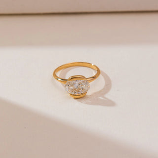 Top view of Modern Half Bezel Diamond Ring in yellow gold, featuring an oval lab-grown diamond secured in a sleek half-bezel setting, displayed on a soft beige backdrop.