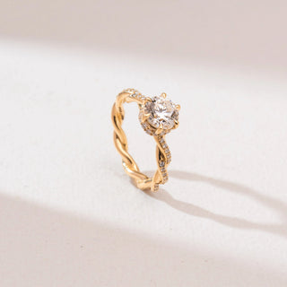 Angled view of Twisted Gold Solitaire Diamond Ring in 14KT yellow gold, featuring a round six-prong centre diamond and pavé-set twisted infinity band.