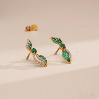 Top-down view of Reia’s 14 KT Yellow Gold Teal Enamel Bouquet Diamond Studs. It highlights the round brilliant diamonds and lush teal enamel floral petals against a clean, cream backdrop.