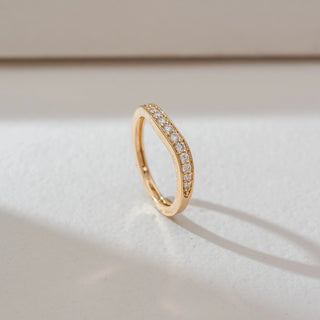 Side angled view of diamond band ring in yellow gold, featuring a slim curved design set with round lab-grown diamonds along the centre. Set on a soft neutral backdrop, it highlights clean form and subtle sparkle.
