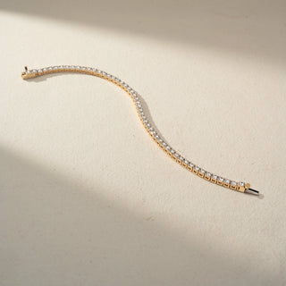 Angled top view of a lab-grown diamond tennis bracelet in 14 KT yellow gold, featuring a continuous row of round brilliant diamonds in a timeless and elegant design.