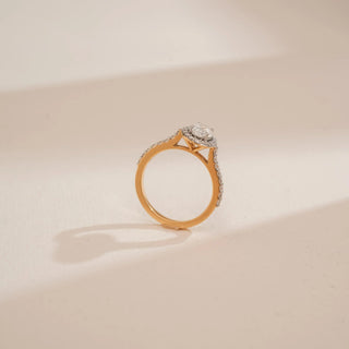 Side profile of Reia’s 18 KT Yellow Gold Oval Halo Diamond Engagement Ring, showing the elevated cathedral setting. Captured against a cream backdrop, it highlights the regal and radiant design.