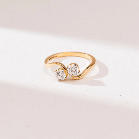 Front view of Radiant Golden Duo Diamond Ring in 14KT yellow gold, featuring two round brilliant-cut diamonds in four-prong settings on a graceful S-shaped bypass band.