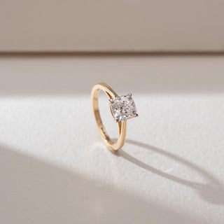 Side angled view of solitaire diamond ring in yellow gold, featuring a square-cut lab-grown diamond set in a minimal four-prong setting. Set on a soft neutral backdrop, it highlights clarity and timeless elegance.