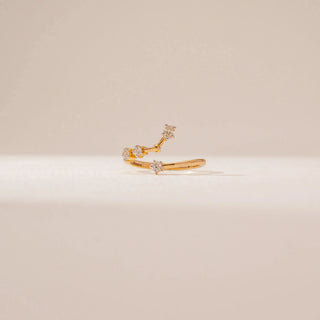 Front view of an open diamond ring in 14KT Yellow Gold, featuring floral diamond clusters along a curved band against a beige backdrop.