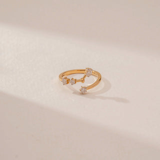 Close-up view of an open diamond ring in 14KT Yellow Gold, featuring floral diamond clusters along a curved band against a beige backdrop.