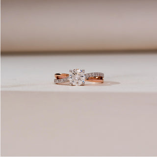 Front view of Intertwined Rose Gold Diamond Ring in 14KT rose gold, showcasing a round brilliant centre diamond with a criss-cross split shank of polished and pavé-set diamond bands.