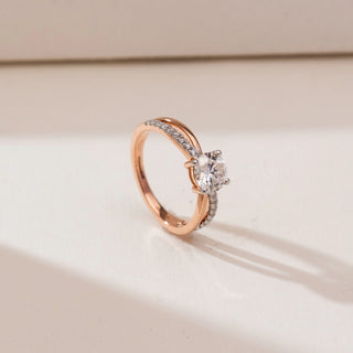 Angled view of Intertwined Rose Gold Diamond Ring in 14KT rose gold, featuring a round centre diamond with a criss-cross split shank of polished and pavé-set diamond bands.
