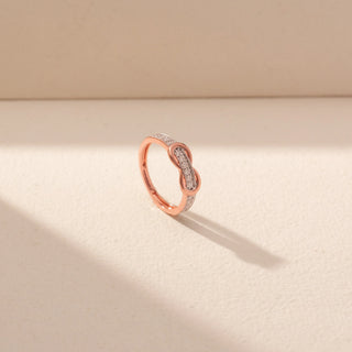 Angled view of Infinity Diamond Ring in 14KT Rose Gold, featuring intertwined loops and a pavé diamond band.