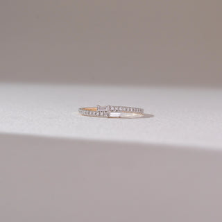 Front view of baguette diamond band ring in yellow gold, featuring twin baguette-cut lab-grown diamonds at the centre with a row of round diamonds along the band. Set on a soft neutral backdrop, it reflects sleek elegance.