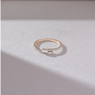 Top view of baguette diamond band ring in yellow gold, featuring twin baguette-cut lab-grown diamonds at the centre with a row of round diamonds along the band. Set on a soft neutral surface, it reflects minimal elegance.