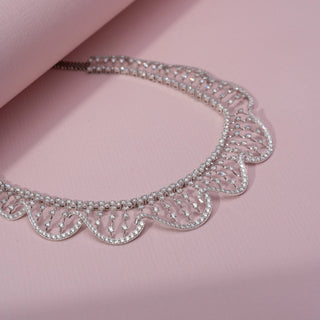 Angled view of a wave-inspired lab-grown diamond necklace in 14KT White Gold, featuring cascading diamond drop accents. Captured against a pink backdrop, the graceful openwork design radiates elegance.