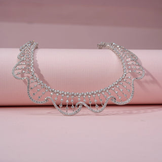 Close up view of a wave-inspired lab-grown diamond necklace in 14KT White Gold, featuring cascading diamond drop accents. Captured against a pink backdrop, the graceful openwork design radiates elegance.