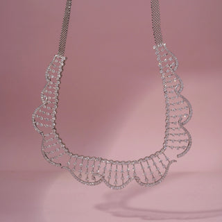 Front view of a wave-inspired lab-grown diamond necklace in 14KT White Gold, featuring cascading diamond drop accents. Captured against a pink backdrop, the graceful openwork design radiates elegance.