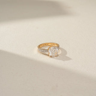 Top view of a solitaire diamond ring featuring a round brilliant-cut center stone and channel-set diamond accents on a polished yellow gold band, displayed in soft natural light.