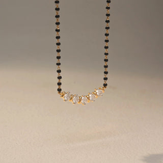 Side view of a diamond mangalsutra necklace in 14 KT Yellow Gold, featuring five round diamonds set in a graceful curved arrangement along a black beaded chain against a neutral backdrop.
