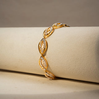  Side view of a yellow gold lab-grown diamond bracelet featuring marquise-shaped links with pavé diamonds, displayed on a neutral jewellery cushion.