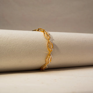 Angled view of a yellow gold lab-grown diamond bracelet featuring marquise-shaped links with pavé diamonds, displayed on a neutral jewellery cushion.