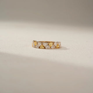 Front view of a diamond eternity band in 14 KT Yellow Gold, featuring alternating heart-shaped yellow and white lab-grown diamonds in a continuous shared-prong design, displayed against a beige backdrop.