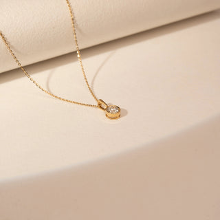 Top view of a 14KT Yellow Gold diamond pendant with a round bezel-set centre diamond and a simple bail.