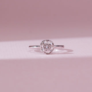 Front view of the Minimalist Six Prong Diamond Ring in 14KT white gold, featuring a round solitaire diamond secured in a classic six-prong setting on a sleek polished band against a soft pink background.