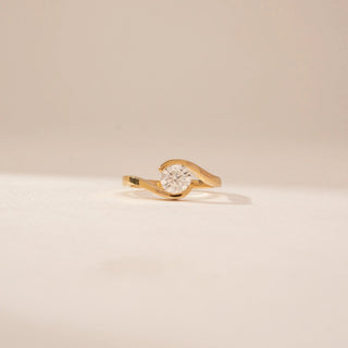 Front view of a 14KT Yellow Gold diamond ring with a round centre stone and flowing crossover band.