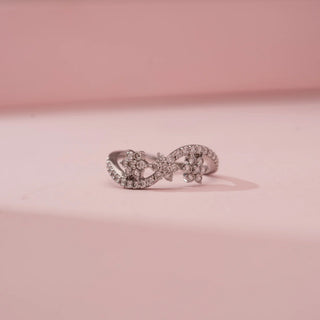 Front view of Reia’s 18 KT White Gold Floral Infinity Diamond Band Ring. Captured against a pink backdrop, the layout highlights the organic arrangement of blossoming flowers.