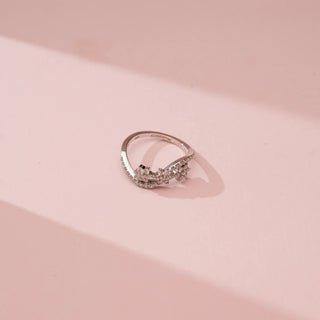 Angled top view of Reia’s 18 KT White Gold Floral Infinity Diamond Band Ring. Captured against a pink backdrop, the layout highlights the fluid, wave-like infinity band and pavé-set floral motifs.