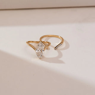 Angled view of Marquise Bypass Split Diamond Ring in yellow gold, showcasing a marquise-cut lab-grown diamond held within an open split bypass band with delicate diamond accents, set on a beige backdrop.