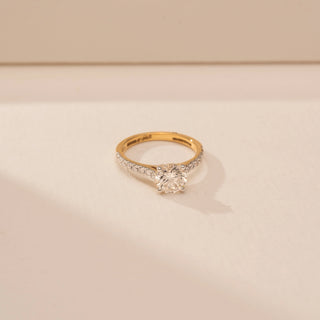 Close - up view of a 14KT White Gold diamond ring, featuring a round centre diamond and diamond-set shoulders.