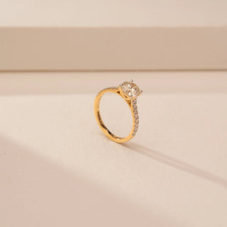 Angled view of a 14KT White Gold diamond ring, featuring a round centre diamond and diamond-set shoulders.