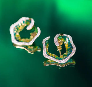 Pair of green enamel and diamond-studded earrings in an organic floral-inspired design, displayed on a vibrant green background.