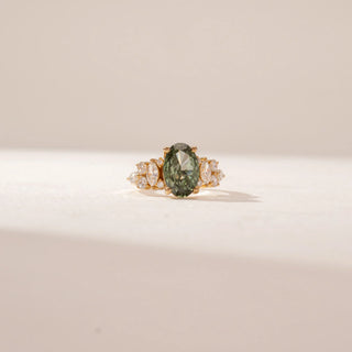 Front view of a 14KT Yellow Gold diamond ring featuring an oval green centre stone and sparkling marquise and round diamond accents.