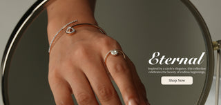 Hand adorned with lab grown diamond ring and elegant rose gold bracelets, reflected in a round mirror. Overlay text reads “Eternal – Inspired by a circle’s elegance” with a ‘Shop Now’ button, highlighting timeless jewellery from Reia lab grown diamonds.