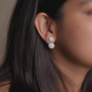 Close-up of Réia’s double-cluster lab-grown diamond earrings in White Gold, adjusting them gently, captured in warm soft lighting for an elegant look.